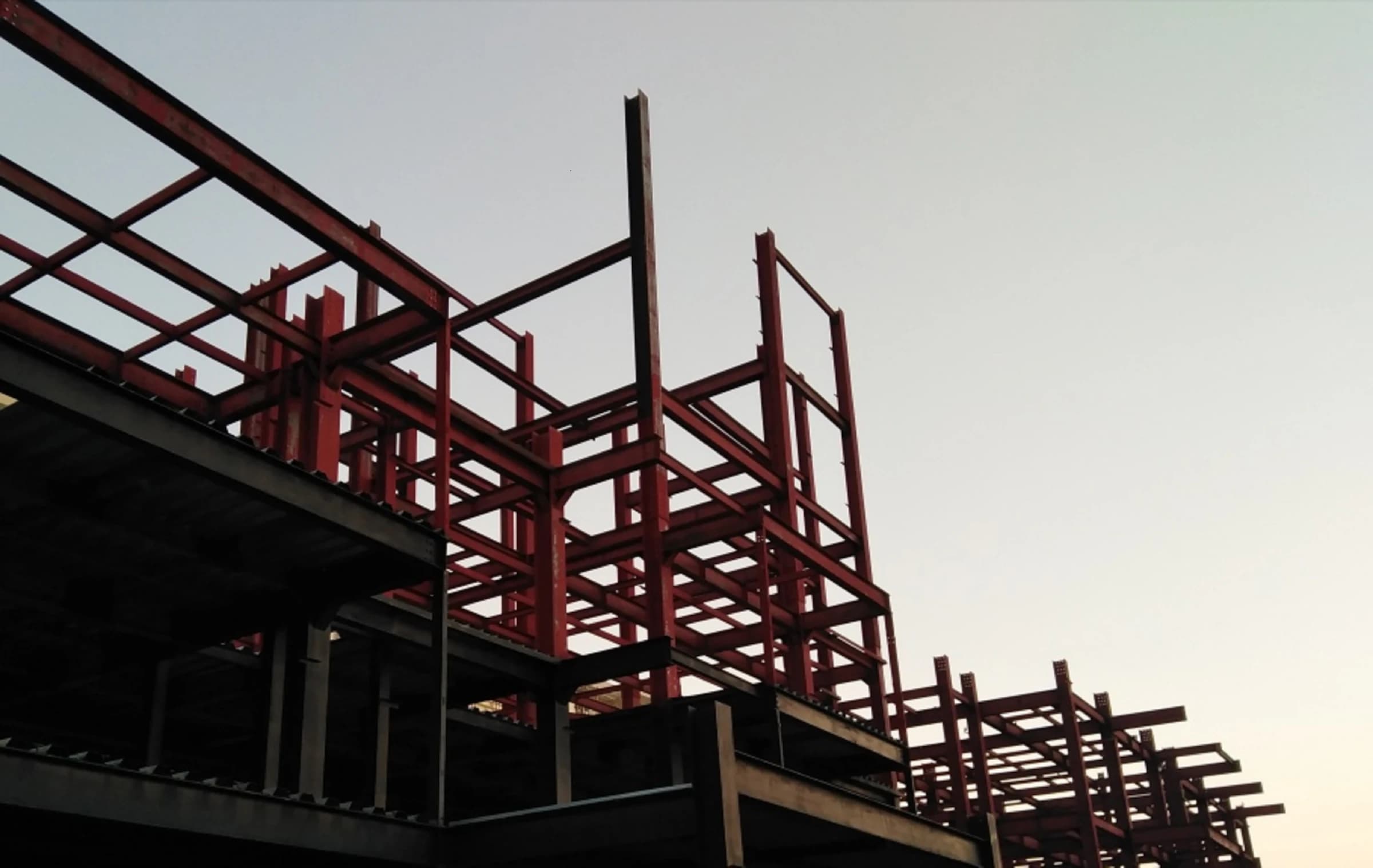 Red iron steel frame of a pre-engineered building standing against an open sky